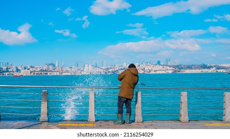 Man Fishing With A Fishing Rod By The Sea And A Rough Sea Wave