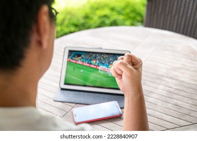 Man with fist up while watching soccer sports game on digital tablet. Live stream or sports online concept.
