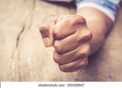A man fists clenched on a wooden table in anger