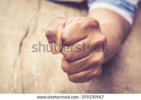 A man fists clenched on a wooden table in anger