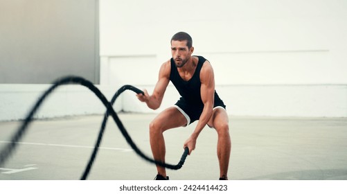 Man, fitness and battle rope exercise for physical training, workout or wellness in the outdoors. Fit, active and serious male person exercising with ropes for intense endurance, stamina or cardio - Powered by Shutterstock