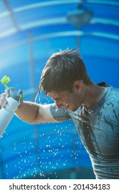 Man Fitness Runner Drinking And Splashing Water In His Face. Funny Image Of Handsome Male Refreshing During Workout