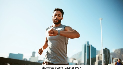 Man, fitness and running with watch in city for workout app, exercise or tracking performance. Active, male person or runner checking wristwatch for steps, calories or monitoring heart rate in town