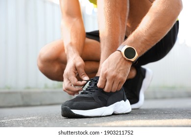 Man With Fitness Tracker Tying Shoelaces Outdoors, Closeup