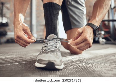 Man, fitness and tying sneakers with laces at gym in preparation for running, workout or exercise. Closeup of male person, runner or athlete tie shoes and getting ready for training at health club - Powered by Shutterstock