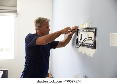 Man Fitting Bracket For Flat Screen TV Onto Wall