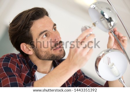man fitting a new bulb into a lamp