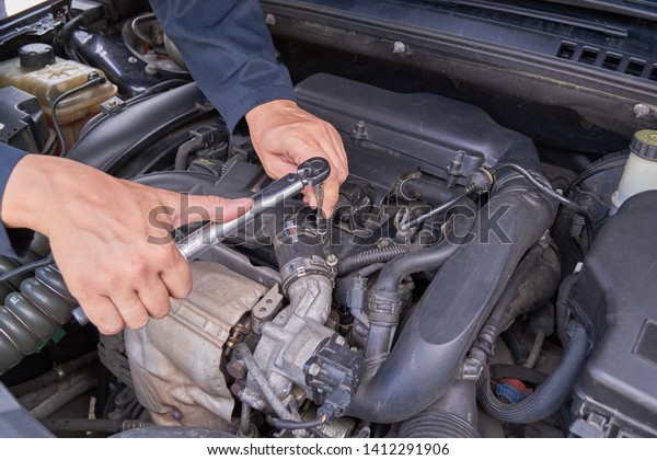 a man fixes a car\
with a torque wrench