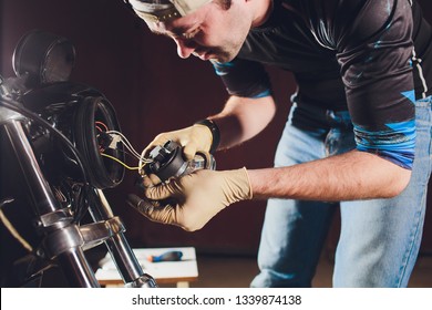 Man Fixing Bike. Confident Young Man Repairing Motorcycle Near His Garage. Replacement Lamp In The Headlamp