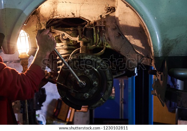 Man fixing brake disk. Car\
mechanic repairing brakes disc on car, indoor repair service\
