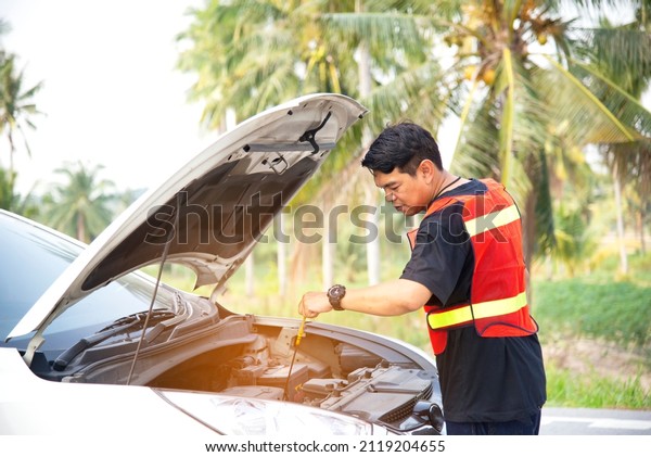 Man fixing a car problem after vehicle\
breakdown on the road,Traffic warning sign on road with car and\
driver on background