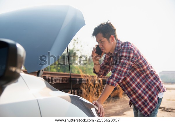 Man fixing a car problem after vehicle
breakdown on the road,Traffic warning sign on road with car and
driver on background