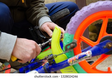 Man Fixing Pedals On Childrens Colorful Bike Close Up