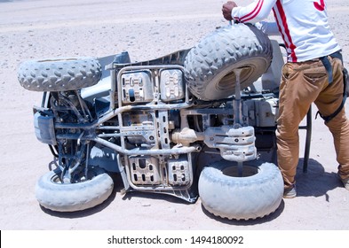 Man Fixing Quad Motorcycle In Desert.Broken Quad Bike Off Road And Arab Man Trying To Fix The Problem.Accident In Four Wheel ATV Driving Safari In Africa