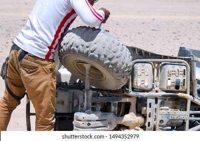 Man Fixing Quad Motorcycle In Desert.Broken Quad Bike Off Road And Arab Man Trying To Fix The Problem.Accident In Four Wheel ATV Driving Safari In Africa