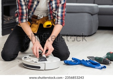 A man is fixing robot vacuum cleaner by hand holding screwdriver to open the cover. Consumables for a robot vacuum cleaner.