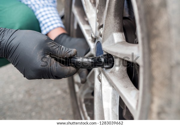 Man fixing wheel in car\
on roadside