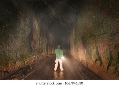 Man with a flashlight exploring in the dark forest