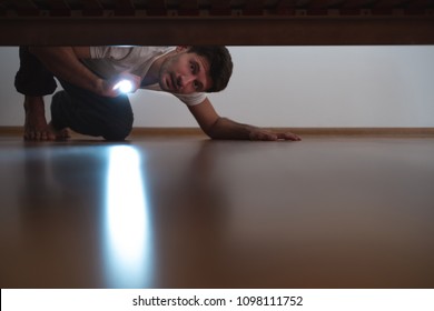 The Man With A Flashlight Looking Under The Bed