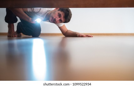 The Man With A Flashlight Looking Under The Bed