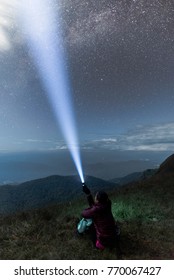 Man with a flashlight, observing beautiful, wide blue night sky with stars and visible Milky way galaxy, clear sky concept and background.