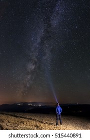 Man with a flashlight trying to light up the night sky and the milky way.