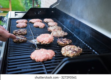 Man Flipping Burgers On Grill