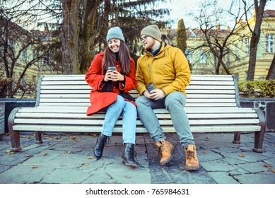 Man Flirting With Woman On The Bench Of City Park In Autumn Day