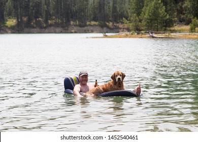 Man Floating On Lake Drinking A Beer With His Dog