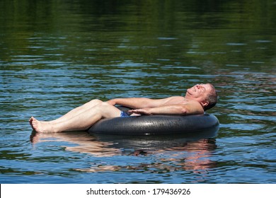 A Man Floating On A Lake On An Inner Tube