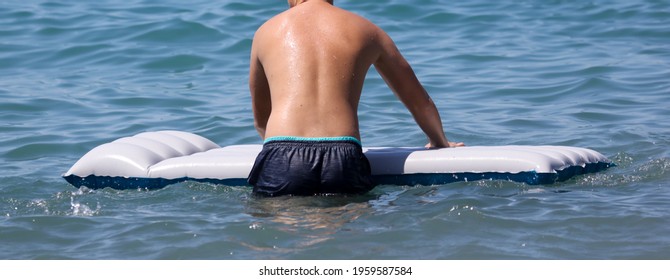 A Man Floats On An Inflatable Mattress In The Sea.