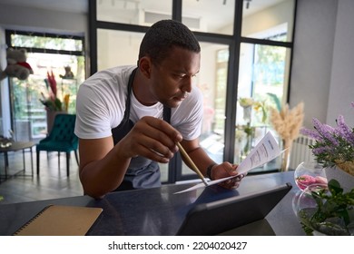 Man In A Flower Shop Is Counting On A Tablet