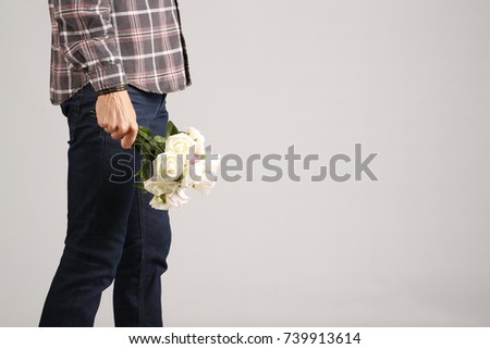 Man in jeans and plaid shirt with some white flowers in his hand