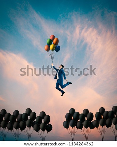 Man flying with colorful balloons. Out of the box concept.