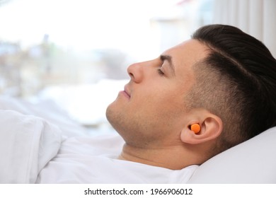 Man With Foam Ear Plugs Sleeping In Bed, Closeup