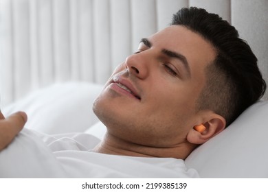 Man With Foam Ear Plugs Sleeping In Bed, Closeup