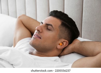 Man With Foam Ear Plugs Sleeping In Bed