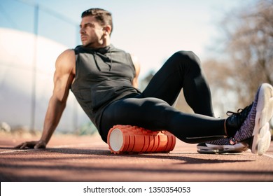 Man foam rolling. Athlete stretches using foam roller.