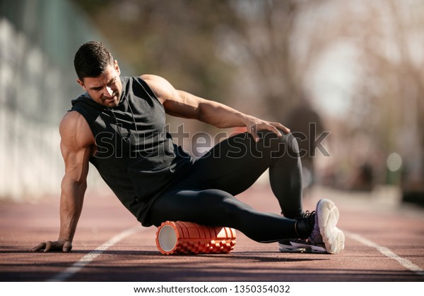 Man\
foam rolling. Athlete stretches using foam\
roller.