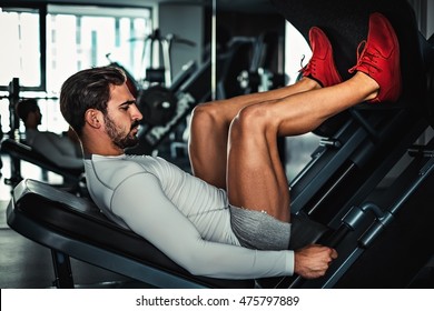 Man focused on training legs on the machine in the gym