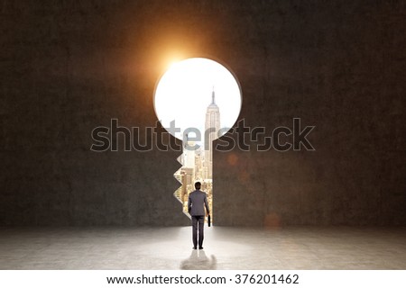 A man with a folder standing in front of a huge keyhole, New York and light seen through it. Black background. Back view.  Concept of finding the way.