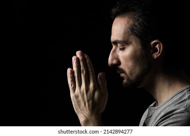 The man folding his hands in prayer to god on a black background. prayer to God for happiness and a better life. Repent of your sins. Unity with God