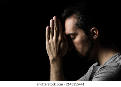 The man folding his hands in prayer to god on a black background. prayer to God for happiness and a better life. Repent of your sins. Unity with God - Shutterstock ID 2143115441