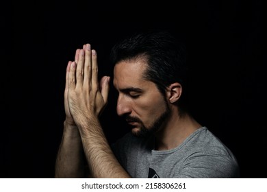 The man folding his hands in prayer to god on a black background. prayer to God for happiness and a better life. Repent of your sins. Unity with God 