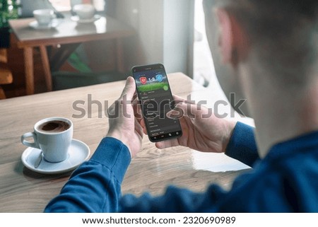 Man follows the online score of the match on his mobile phone in a cafe. Modern app design interface concept