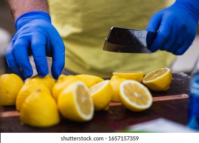 A Man With Food Prep Gloves On Uses A Knife To Slice And Prepare Lemons