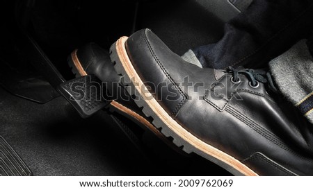 Man foot and accelerator and brake pedal inside the car or vehicle and copy space which black color leather shoe stepped on it for speed up or control automobile pace power. Automobile Driving concept