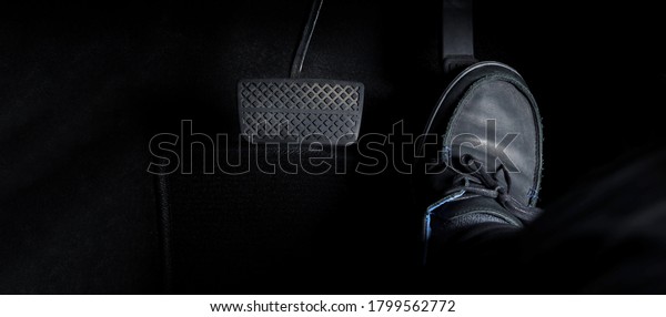 Man foot and\
accelerator and brake pedal inside the car or vehicle and copy\
space which black color leather shoe stepped on it for speed up or\
control automobile pace power.\
