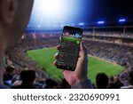 Man at a football match follows the odds and the current score. The concept of online sports betting. Football stadium and crowd in the background