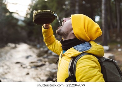 man in the forest drinks water from canteen - Powered by Shutterstock